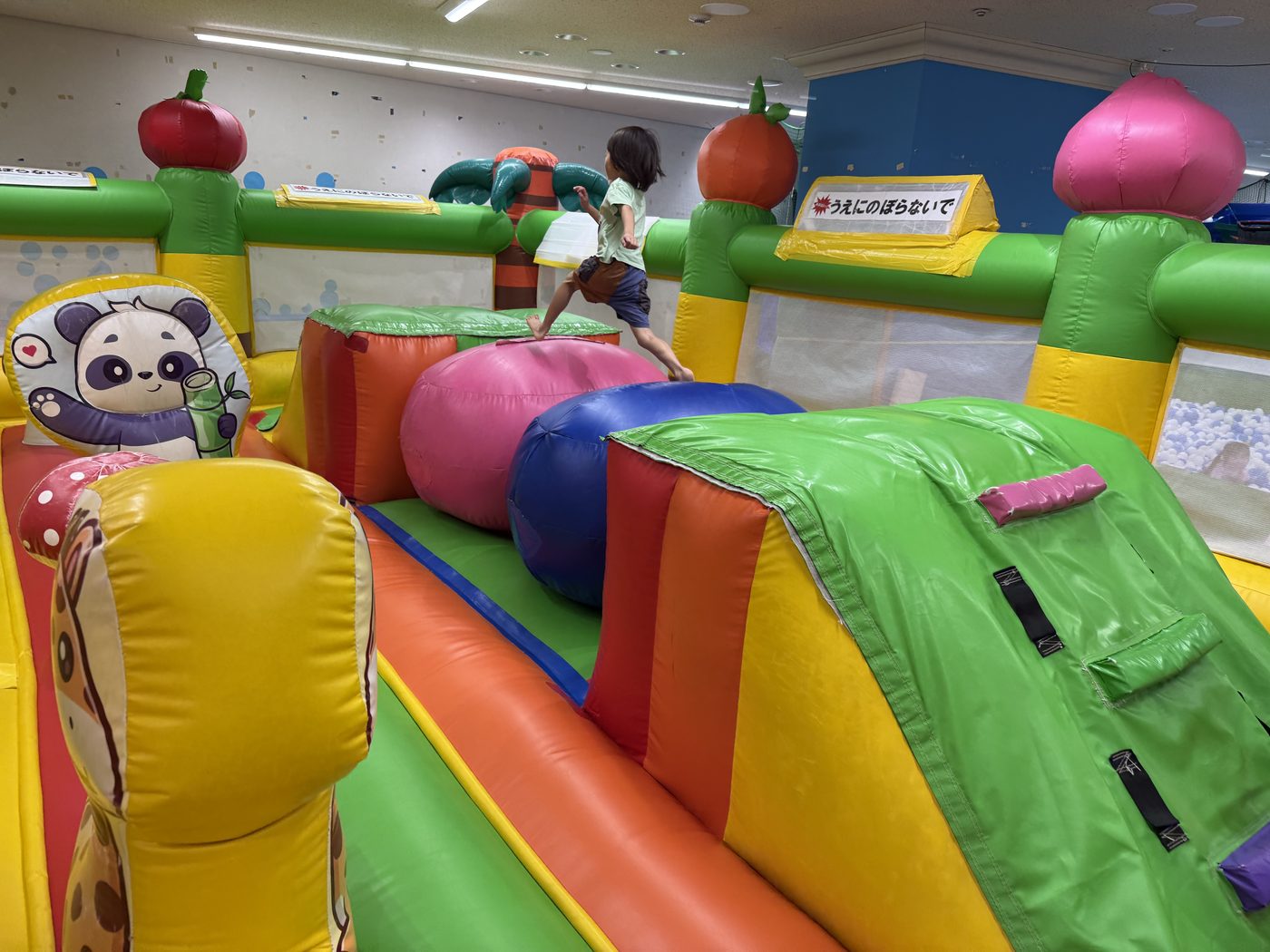 ふわふわ遊具の中を裸足で走る子どもの後ろ姿