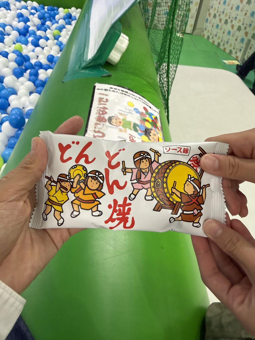 ラップに包まれた駄菓子を子どもの手が持っている