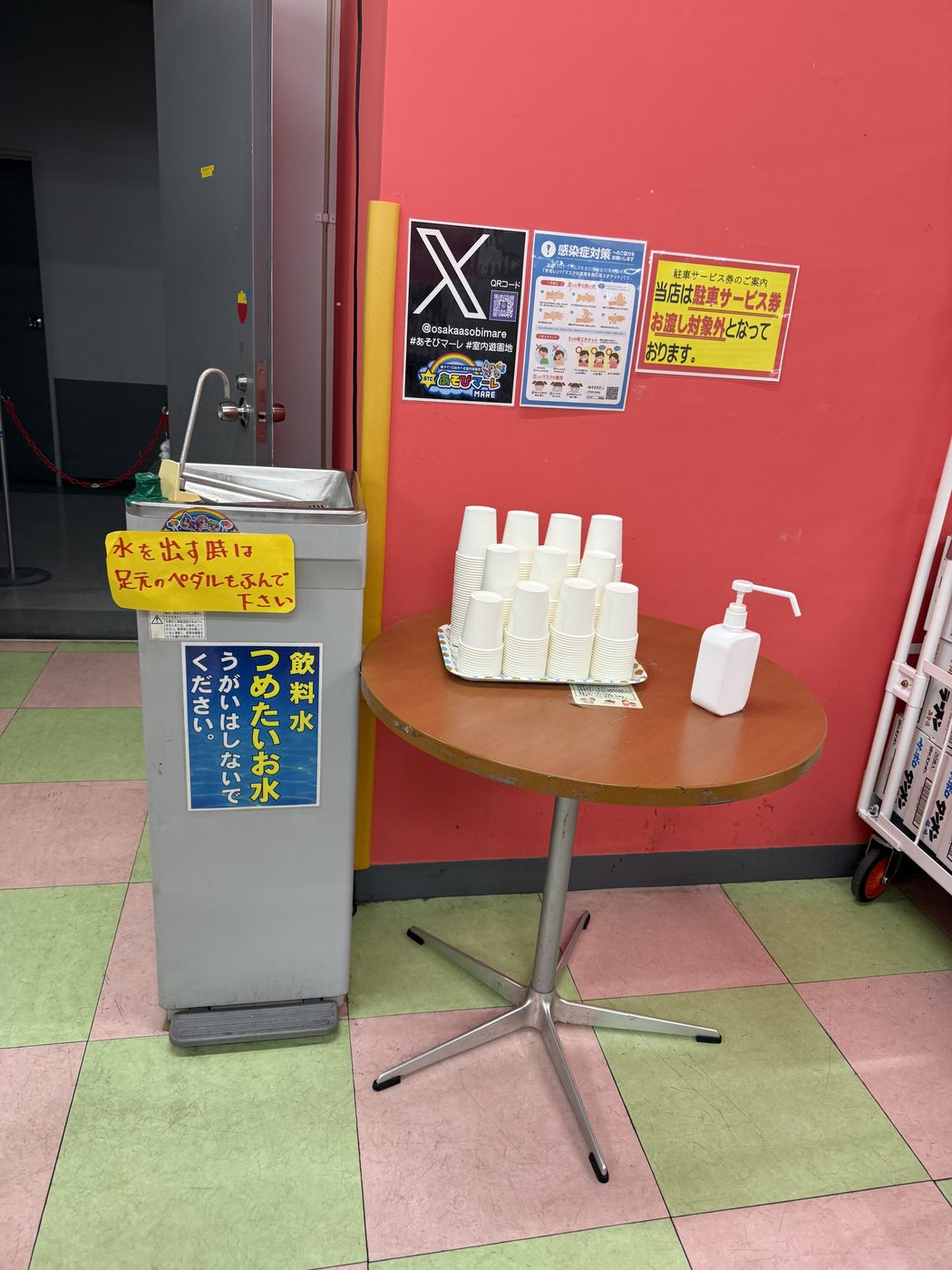 銀色の冷水機と紙コップが積まれた丸テーブル