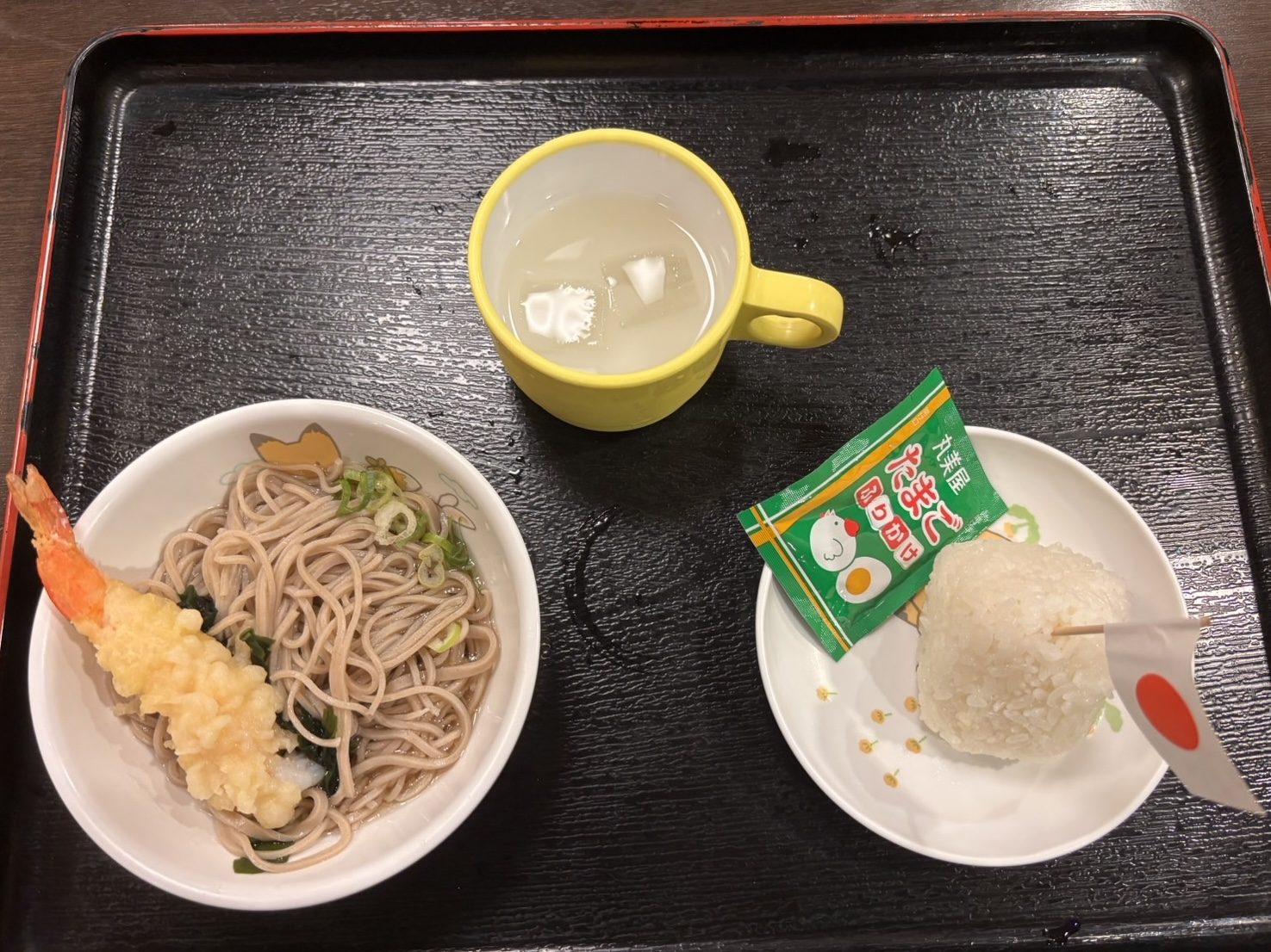 お盆にのったお子様そばセット。海老天ぷらののったそば、ふりかけ付きのおにぎり、ジュース
