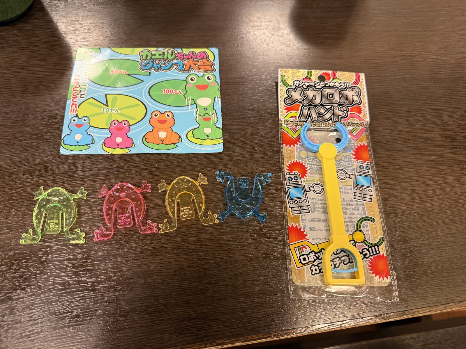 テーブルに並べられた、カエルのジャンプ大会のおもちゃとメカロボハンド