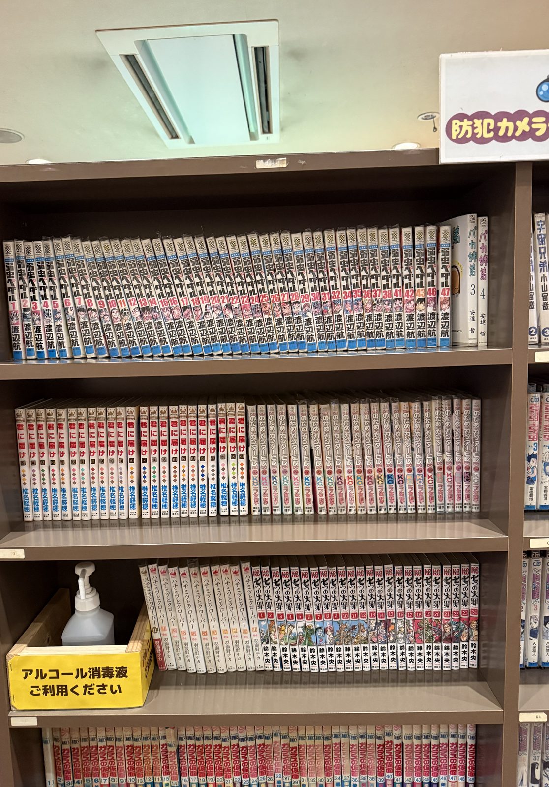 別の棚に並ぶ漫画と、横に置かれたアルコール消毒液