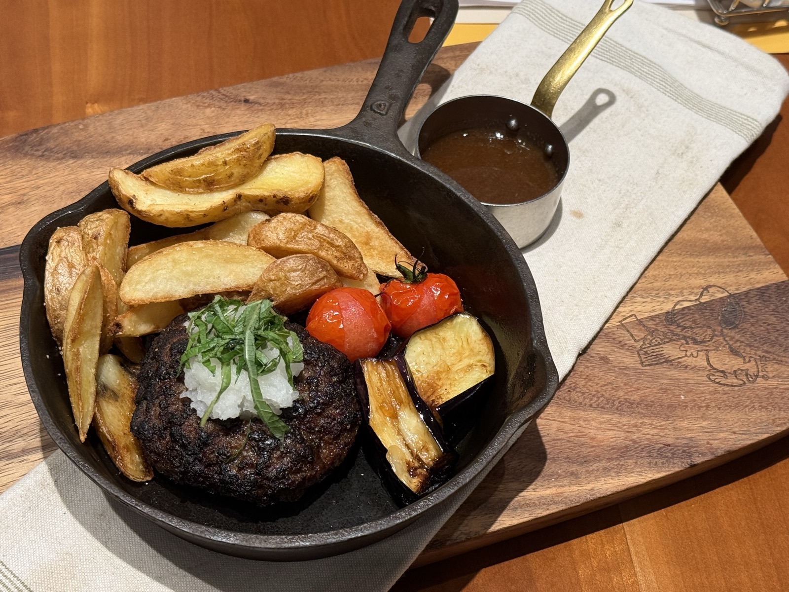 スキレットに入った淡路牛のハンバーグ。大根おろしと大葉がのっていて、ソースは別添えの小さな鍋で添えられている