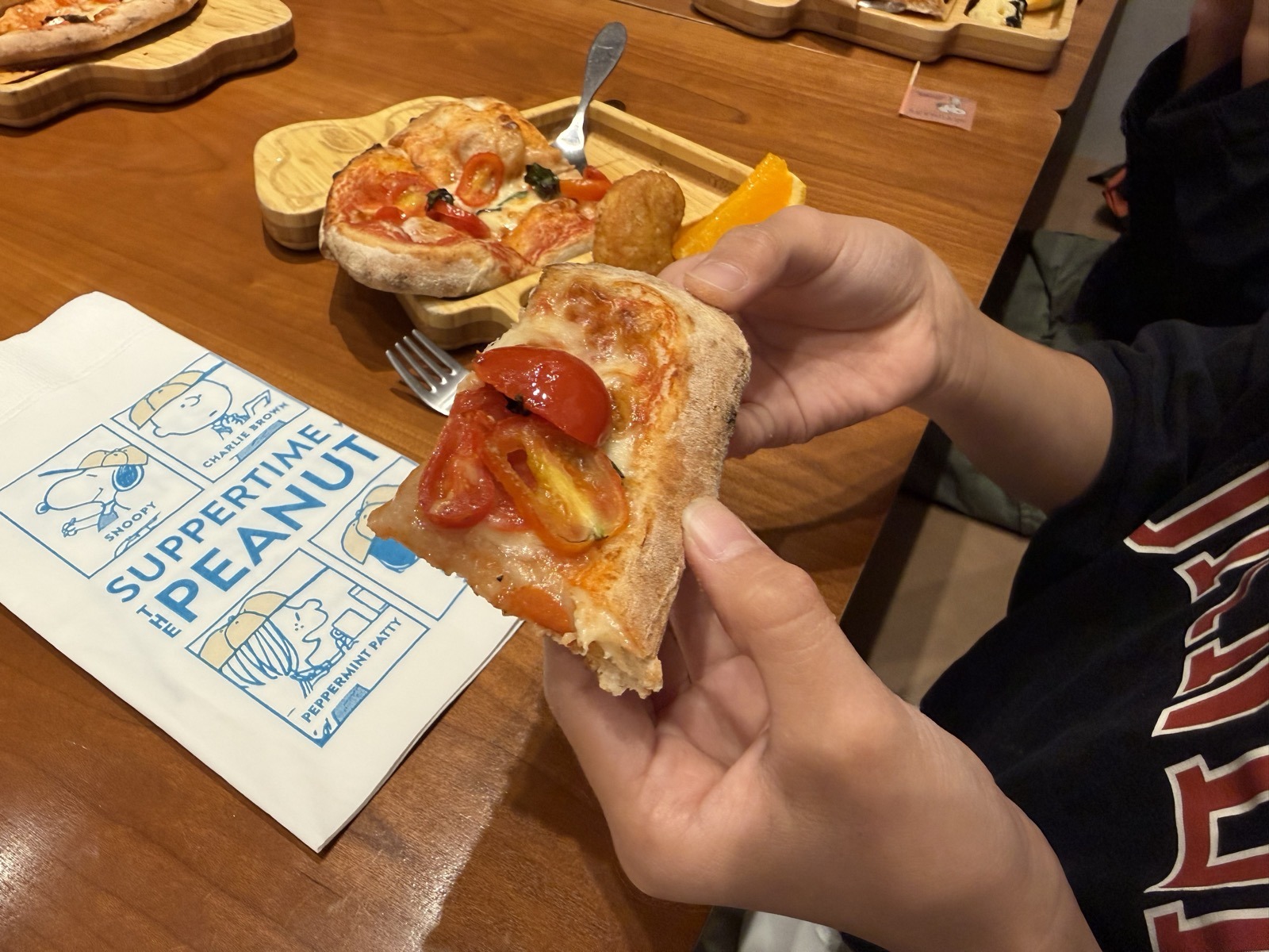 キッズプレートのピザを手に持っている様子。縁がぷっくり膨らんだピザ
