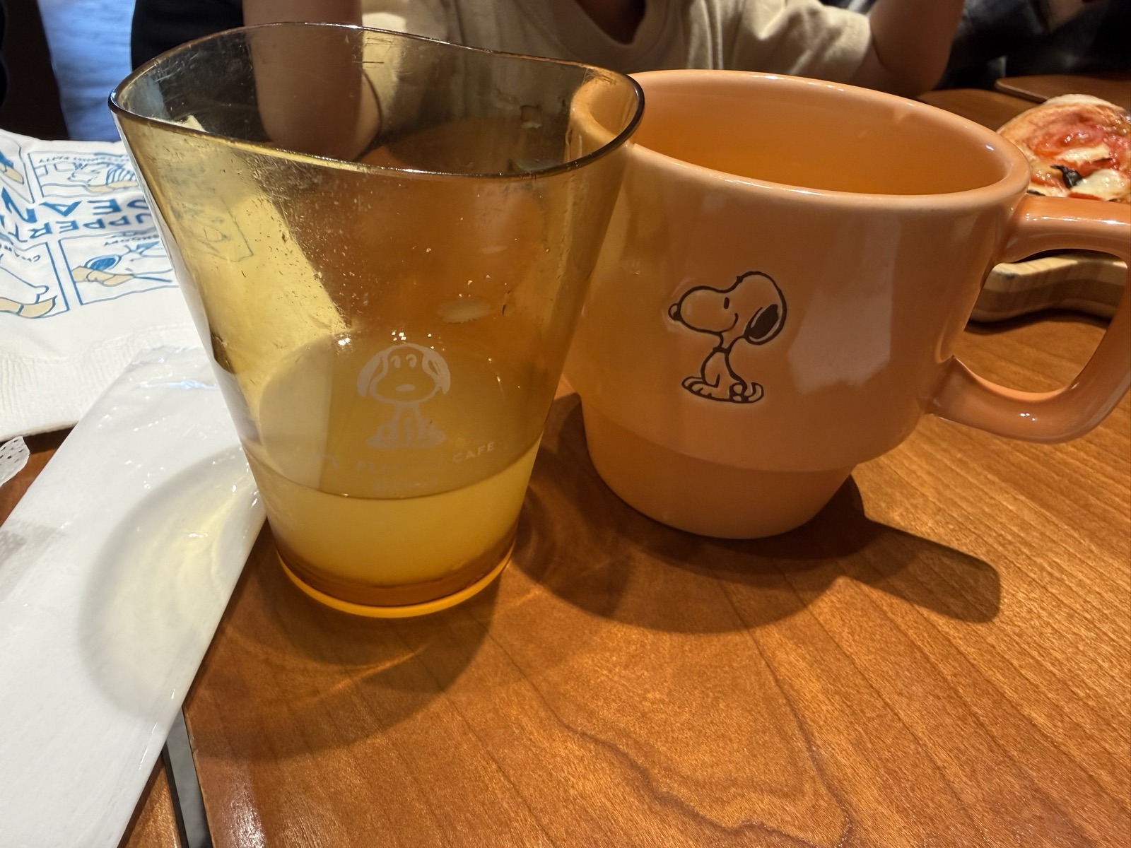 オレンジ色のスヌーピーのマグカップとPEANUTS CAFEのロゴが入ったグラス